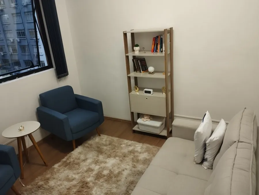 Sala de atendimento com poltronas e estante